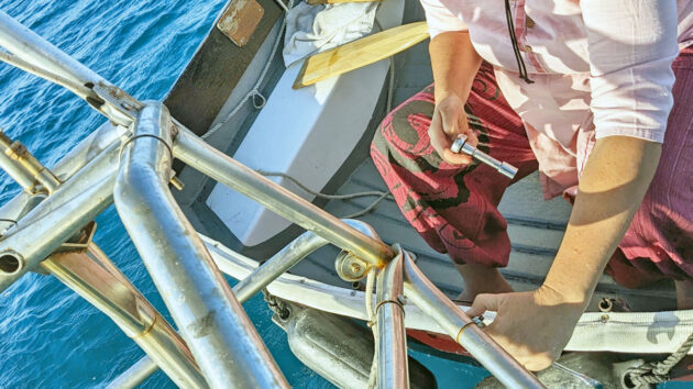 A woman removing the paddle of a Monitor wind vane self-steering system