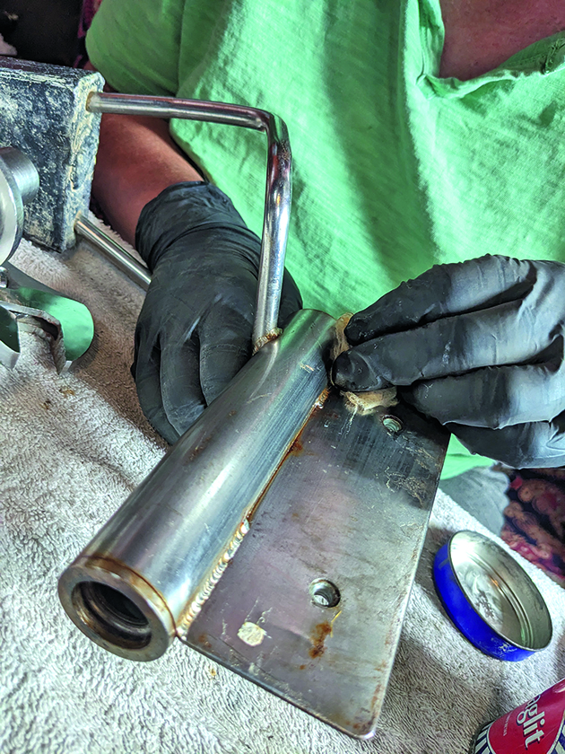 A person cleaning parts of a Monitor wind vane for a boat