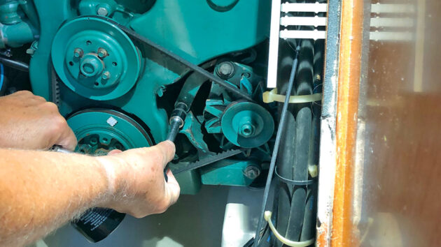 A man alternator belt tensioning on his boat