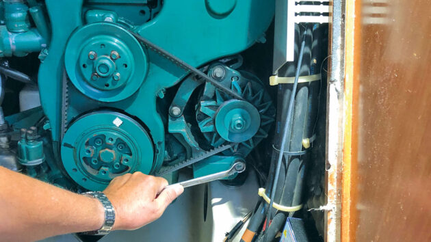 A man doing alternator belt tensioning on his boat engine