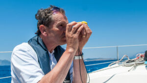 A man using a handbearing compass as part of pilotage for a boat