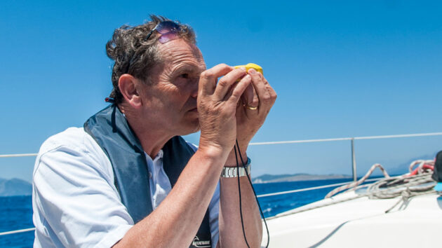 A man using a handbearing compass as part of pilotage for a boat