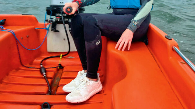 A woman on a boat wearing white Helly Hansen Skagen F2 deck shoes
