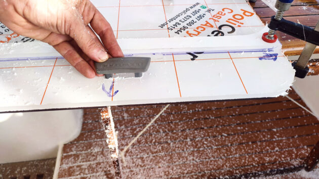 A man using parts of a hatch to mark out holes for boat hatch replacement