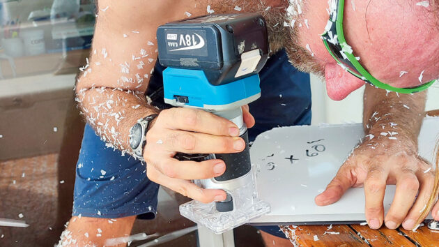 A man cutting acrylic for boat hatch replacement on a catamaran