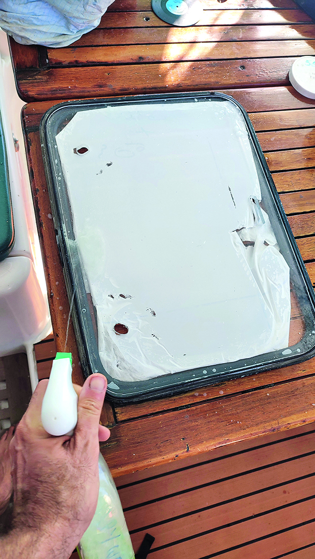 Soapy water being sprayed onto a hatch frame on a boat