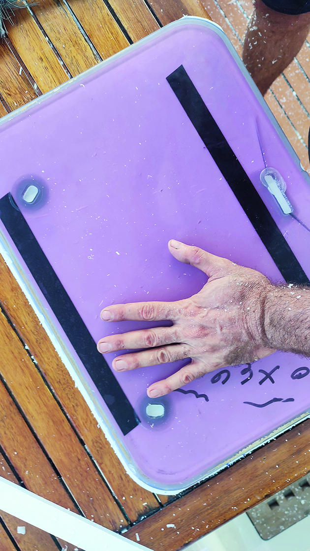 A man drawing a template while carrying out boat hatch replacement on a yacht