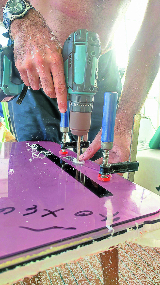 A man drilling holes into perspex