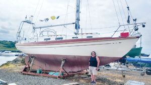 A woman standing by a boat that she bought for her dream voyage