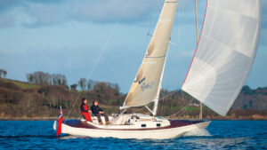 A Rustler 33 yacht sailing close to the coast