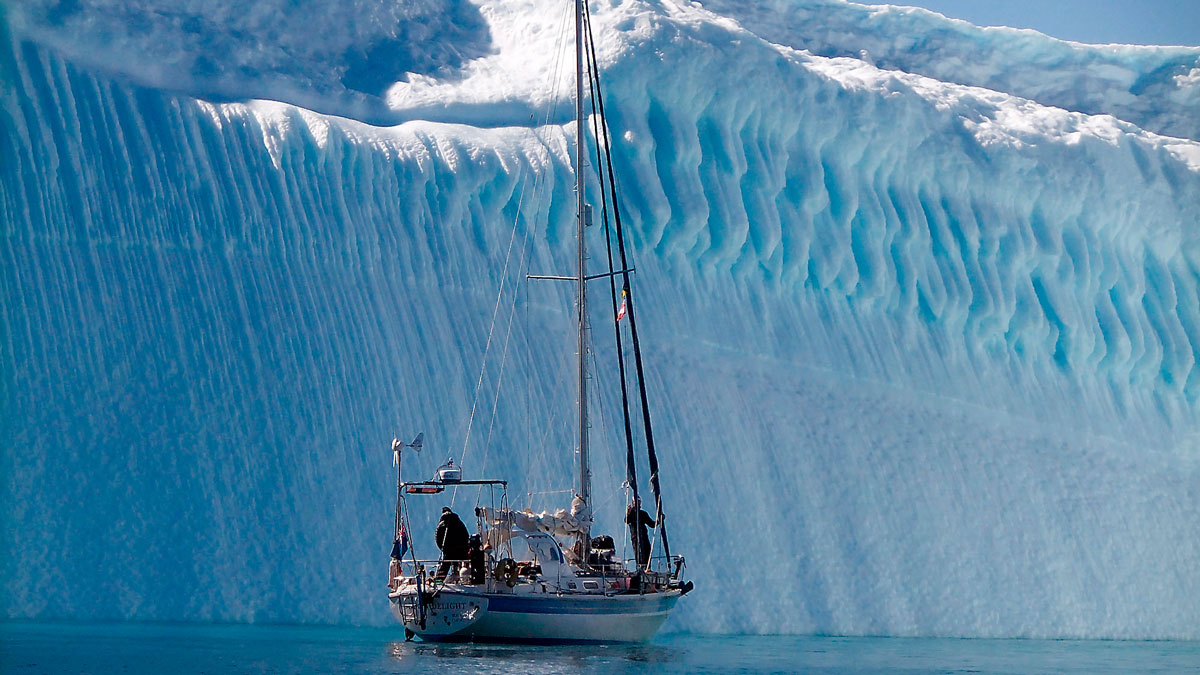 A boat sailing by an ice berg during a high latitude cruise