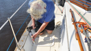 A man caulking portlight trim before installation on a boat