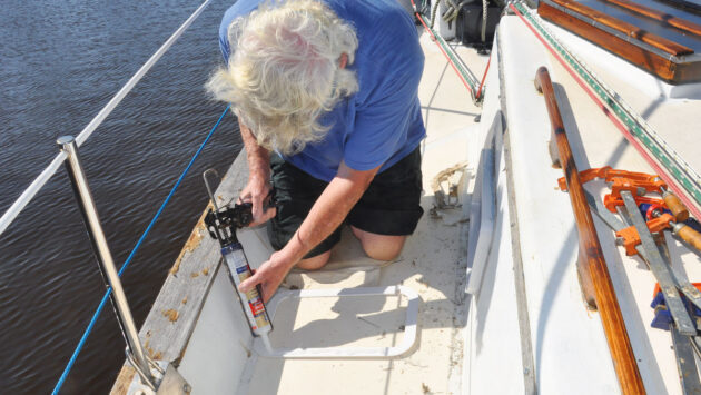 A man caulking portlight trim before installation on a boat