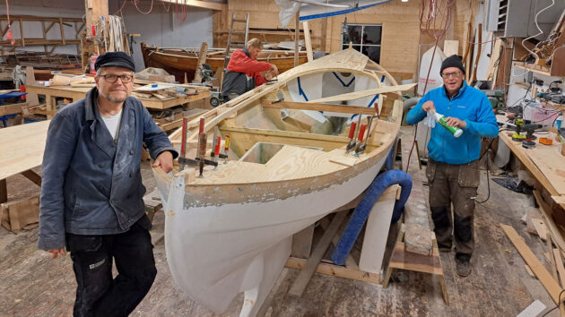 Men in a shed building a boat