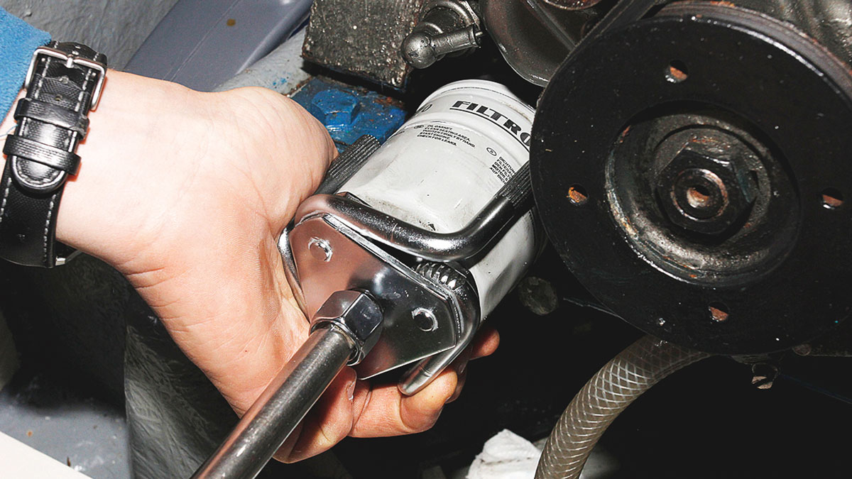 A person changing an engine filter on a boat