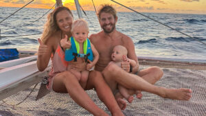 Sailing with family: two parents with their children on the net of a catamaran