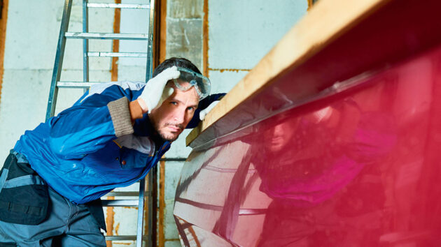 A man looking at a mirror finish on the topsides of a boat