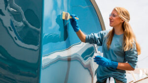A woman painting a boat to get a mirror finish