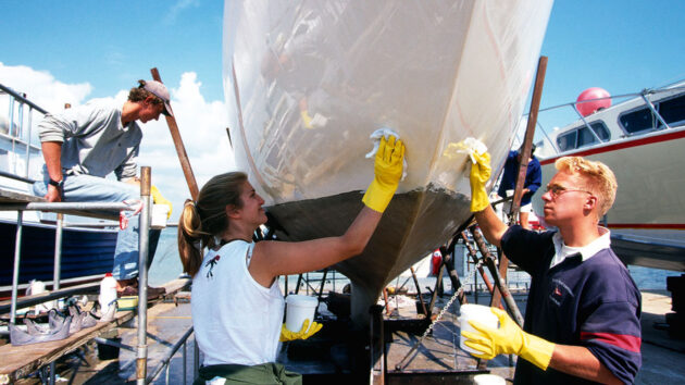 A group of people polishing the hull of a boat