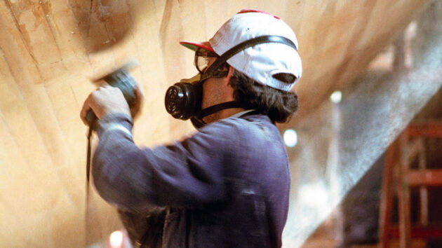 A man sanding the hull of a wooden boat