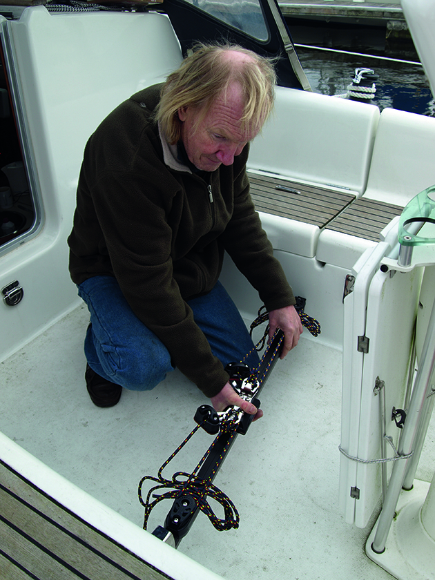 A man fitting a removable mainsheet track to a yacht