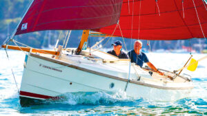 Two men sailing a Cornish Shrimper 19 boat with a red sail