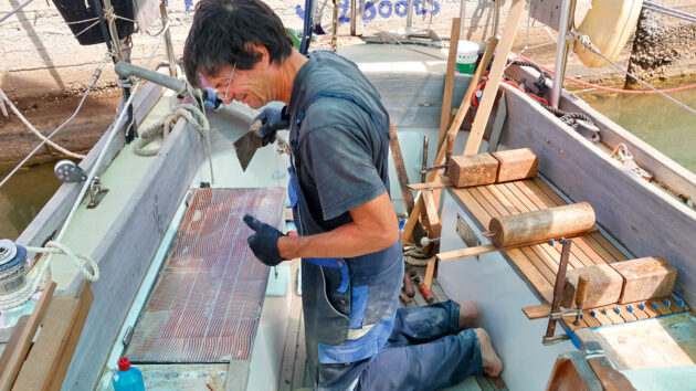 A man glueing teak planks to a cockpit of a boat
