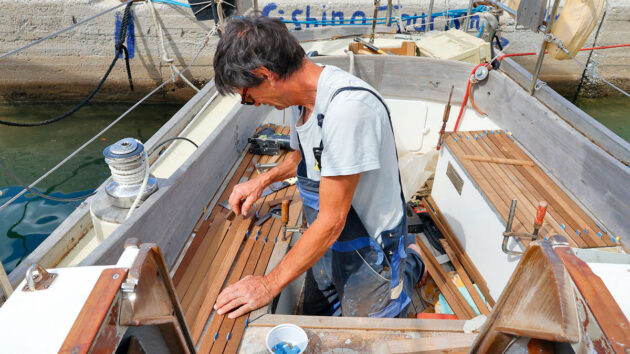 A man laying teak planking in the cockput of a boat