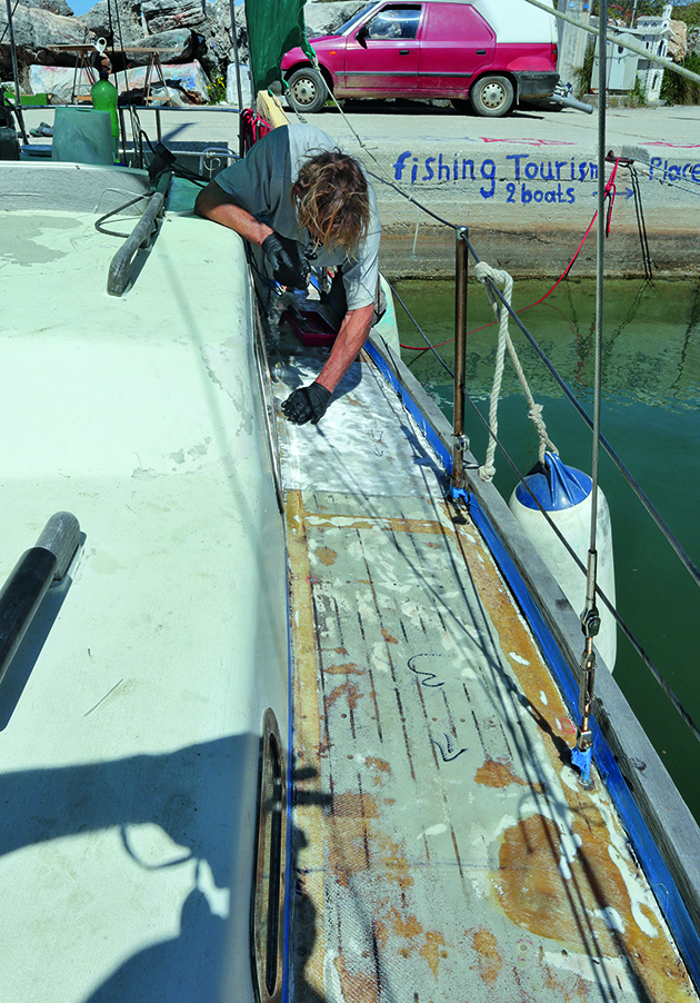 A man laying glass mat on a deck ahead of applying SoftSand coating