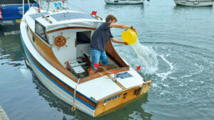 A man emptying a boat after it has sunk