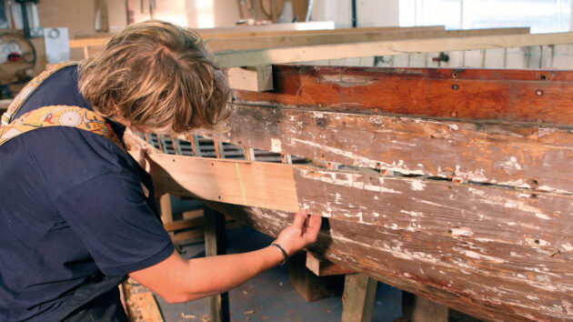A man replacing a hull plank on a boat