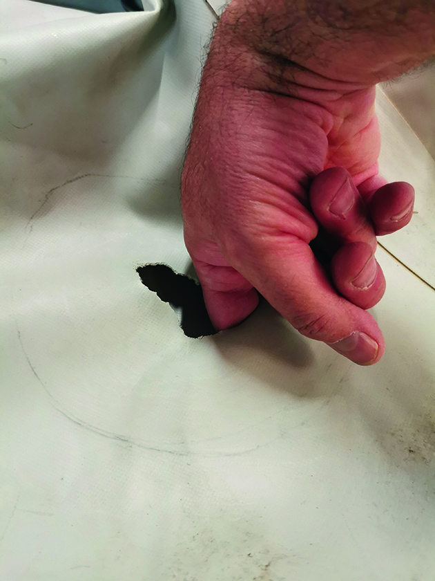 A man sticking his fingers in a hole while repairing inflatable dinghy