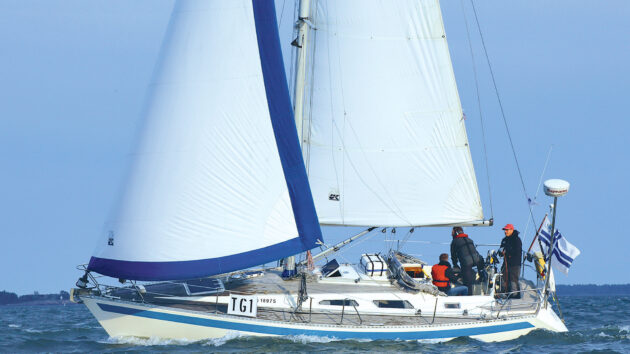 A yacht with a white hull and white sails with a blue border sailing