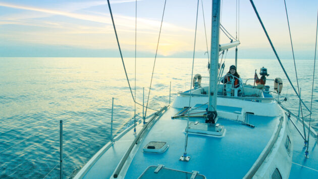 A person in the cockpit of a boat sailing