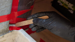 A man wearing Black Mamba disposable gloves while applying epoxy to a boat