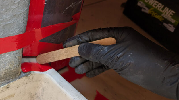 A man wearing Black Mamba disposable gloves while applying epoxy to a boat