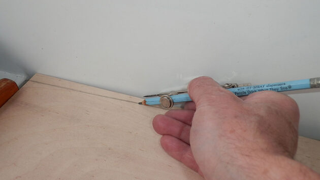 A man using compasses t measure a curve of a panel