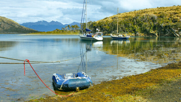 A dinghy beached and attached to a line to a boat