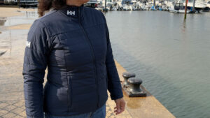A woman wearing a jacket on a quayside with boats in the background