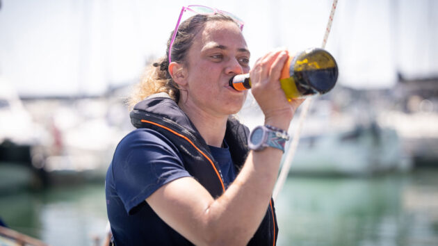 Solo sailor Jazz Turner, first disabled person to complete a non-stop, unassisted circumnavigation of the UK and Ireland, drinks from a champagne bottle at the voyage finish at Brighton Marina. Credit: Fergus Kennedy
