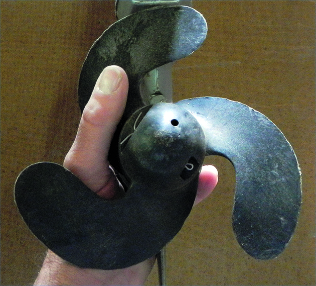 A person holding a left-handed propeller for a boat