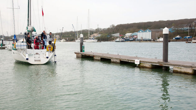 A yacht reversing in a marina to a pontoon
