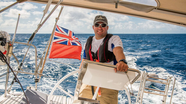 A man at the wheel of a yacht while sailing offshore