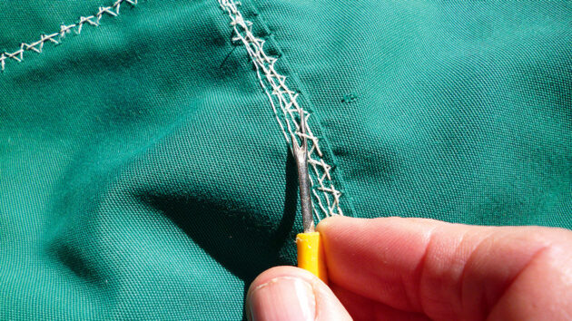 A man unpicking stitching from fabric
