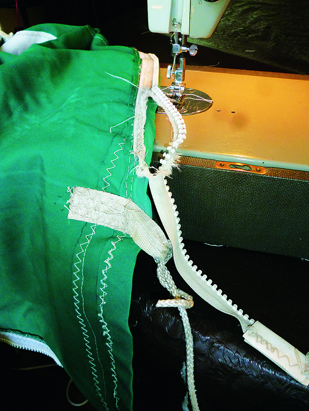 A zip coming away from a main sail cover being repaired with a sewing machine