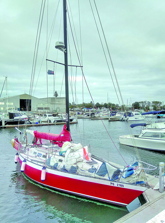 A boat with a red hull moored by a pontoon