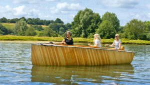 A boat built by BlueTree boatbuilders being motored along a river