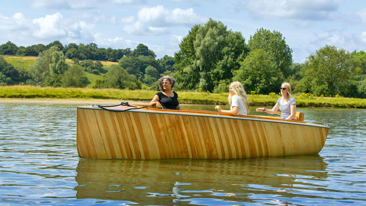 A boat built by BlueTree boatbuilders being motored along a river
