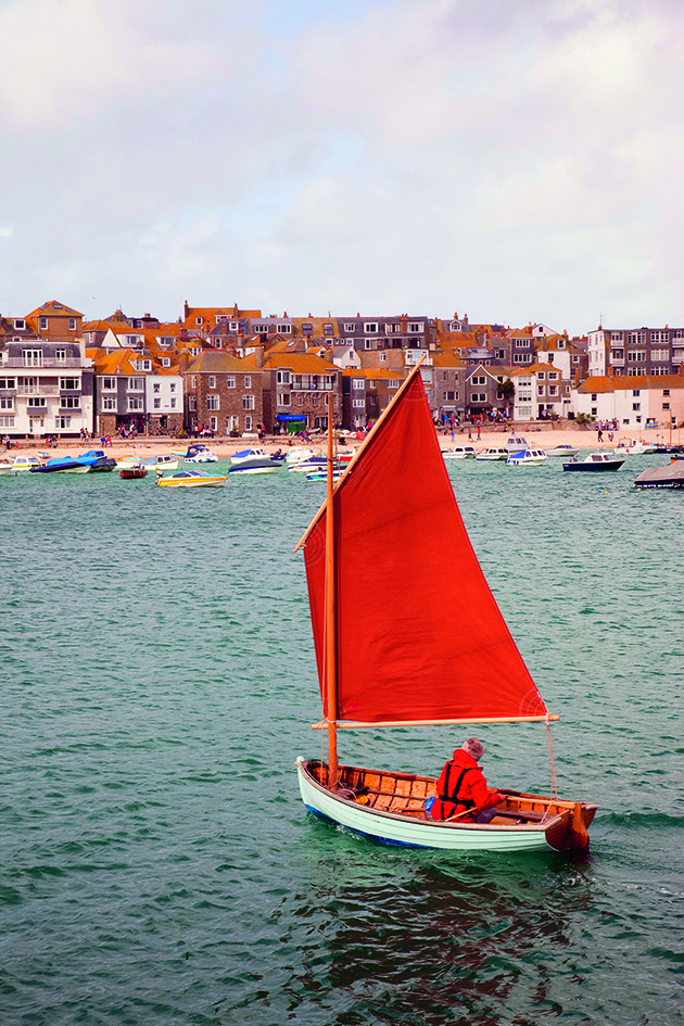 A boat with a red sail with an unstayed rig