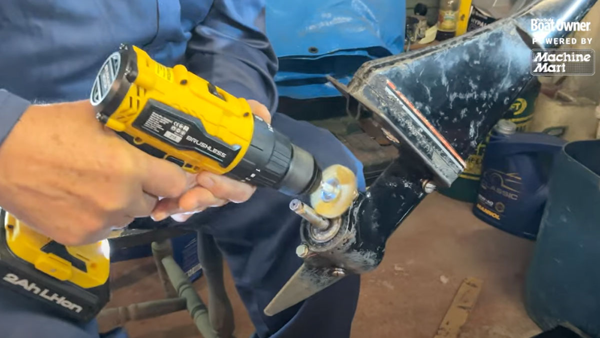 A man cleaning an engine leg on an outboard engine